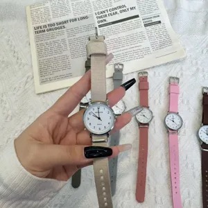 Close-up detail of minimalist quartz watch with casual canvas strap and clear dial.