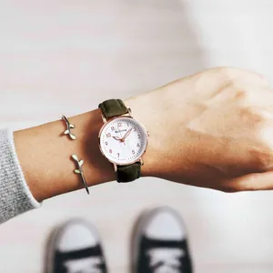 Green strap quartz wristwatch with white dial and rose gold case worn on wrist detail shot