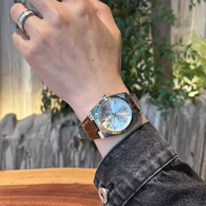 Primo piano di un orologio al quarzo da uomo con cinturino in pelle marrone e quadrante argento.