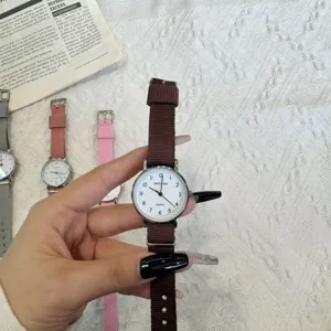 Detailed view of women casual quartz watch with brown canvas strap and white dial close up