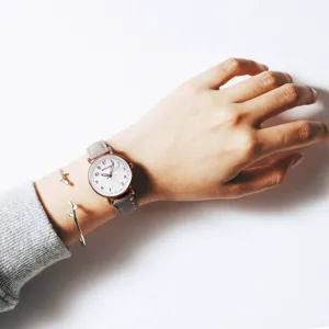 Detailed view of women quartz watch with grey strap, rose gold case and white dial.