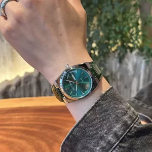 Dettaglio polso orologio al quarzo con quadrante verde, stile casual elegante in pelle.