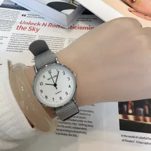 Minimalist women quartz watch with grey canvas strap, student exam style, detail view.