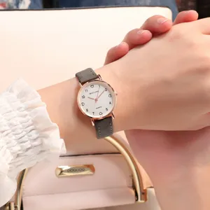 Montre quartz femme cadran minimaliste petit avec bracelet cuir gris, detail poignet.