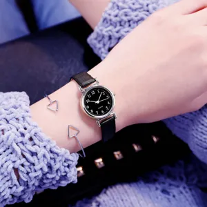 Close-up detail of women small dial quartz watch with black leather strap and chic bracelet.