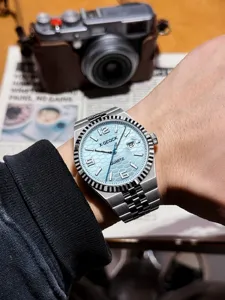 Detailed shot of a stylish men quartz watch with light blue dial, metal strap and fluted bezel.