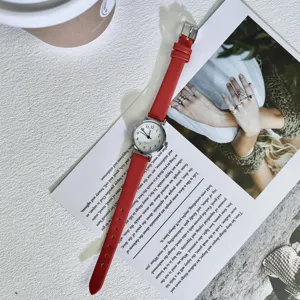 Detailed closeup shot of a chic red leather strap quartz watch with a small white dial.