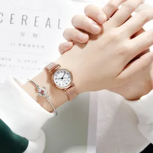 Detail shot of minimalist rose gold mesh watch with white dial and elegant flower bracelet.