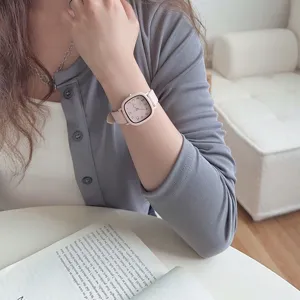 Detailed close-up of a pink square watch on wrist, featuring minimalist dial and soft strap.