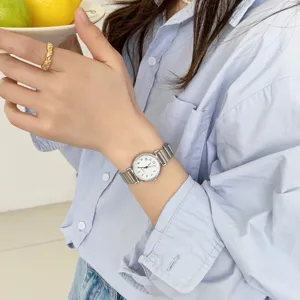 Close-up of women's vintage quartz watch with metal band and round dial, elegant daily wear.