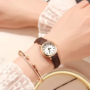 Vintage small dial quartz watch for women with brown leather strap and elegant wrist charm.