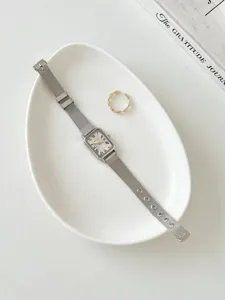 Vista dettagliata di un orologio da donna rettangolare con numeri romani e cinturino in maglia.