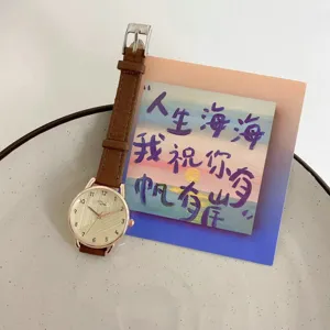 Minimalist women's quartz watch detail, brown leather strap and rose gold case, stylish.