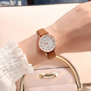 Gros plan détaillé d'une montre quartz minimaliste pour femme avec bracelet en cuir marron.