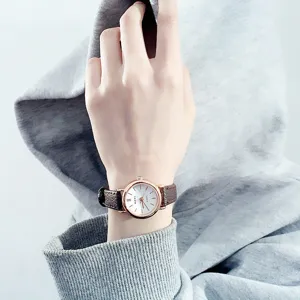 Close-up detail of women quartz watch with brown leather strap and rose gold bezel design.