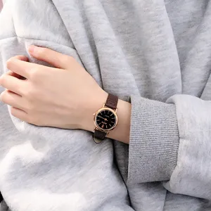 Close-up detail shot of a vintage style women quartz watch with black dial and brown leather strap.