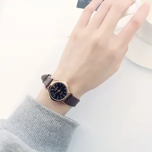 Minimalist vintage style women's quartz watch with black dial and brown leather strap.