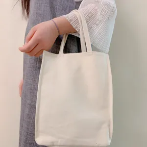 Close-up detail of plain cotton canvas tote bag, handheld lifestyle view for casual daily use.