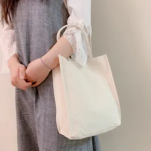 Detail shot of a plain canvas tote bag, featuring sturdy handles and blank surface for DIY art.