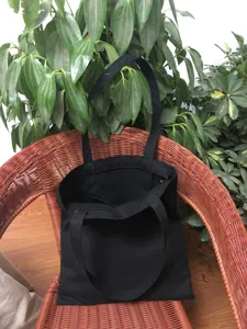 Vista de detalle de bolso tote de lona negra lisa, bolso informal simple para uso diario.