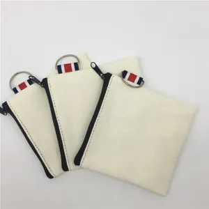 Close-up detail of white canvas coin pouch with zipper, metal ring and striped ribbon loop.