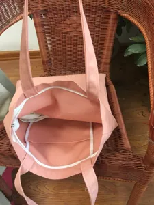 Vista detallada del bolso de lona rosa que muestra el cierre de cremallera y bolsillo.