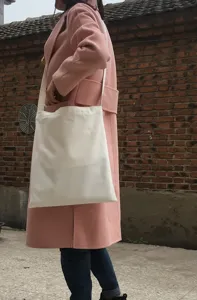 Detailaufnahme einer schlichten weißen Canvas-Tasche über der Schulter, lässiger Stil.