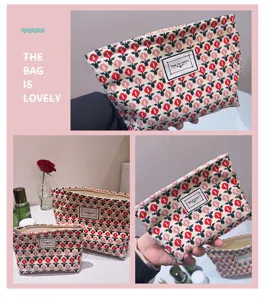 Close-up detail of floral canvas cosmetic pouch featuring vibrant red pattern and fabric label.
