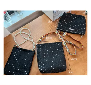 Vue détaillée du sac bandoulière noir à pois avec sangle colorée et poignée en perles.