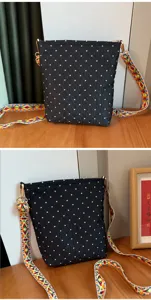 Sac bandoulière noir à pois avec sangle ethnique colorée pour les déplacements quotidiens.
