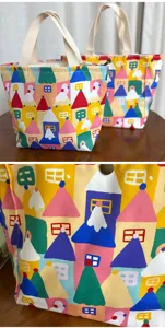 Detalles en primer plano de la bolsa bento de lona con vibrantes patrones de casas y asas resistentes.
