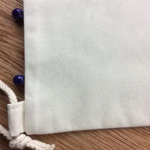 Close-up detail of plain canvas drawstring bag with blue beads, perfect for DIY and craft.