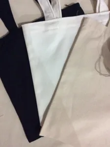 Detail view of plain blank canvas tote bags in black, white and natural beige colors.