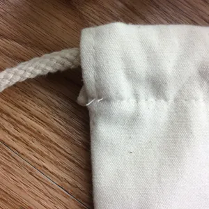Plain canvas drawstring bag detail, durable cotton fabric and sturdy rope cord for DIY use.