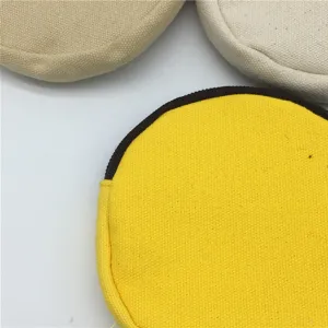 Nahaufnahme von runden Leinwand-Münztaschen, zeigt Textur, Reißverschluss und Farben.