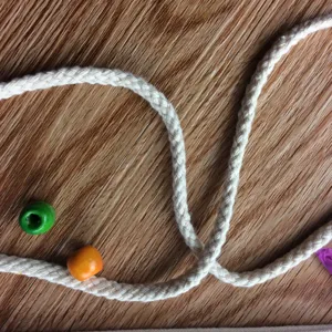 White braided drawstring and colorful wooden beads detail for DIY canvas backpack craft project.