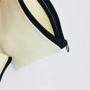 Close-up detail of beige canvas zipper pouch, neat black zipper edge, plain background