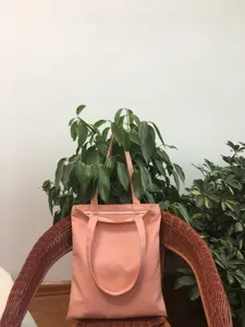 Vista detallada de un bolso de lona rosa liso, ideal para desplazamientos y uso diario.