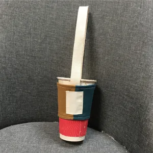 Detailansicht des farblich abgesetzten Milchtee-Becherhalters aus Stoff mit Tragegriff und Patchwork.
