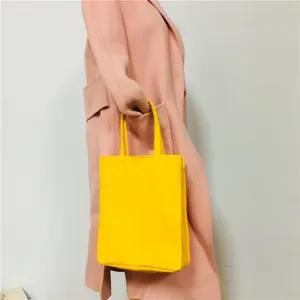 Solid yellow canvas tote bag detail view, casual everyday handheld shopping bag close up.