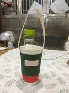 Detailansicht des grünen Stoff-Becherhalters mit beigefarbenem Henkel für Getränkebecher.