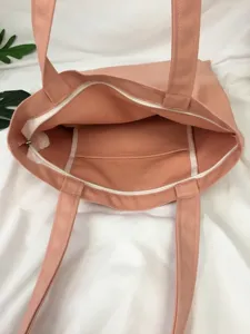Bolso tote de lona rosa con cierre de cremallera y un practico bolsillo interior.