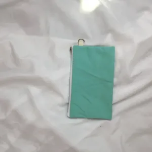 Mintgrüne Canvas Münztasche Detailansicht mit weißem Reißverschluss und kleinen Metallring.