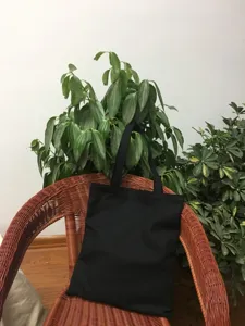 Vista detallada del bolso de lona negro, diseño de color sólido simple para el uso diario.