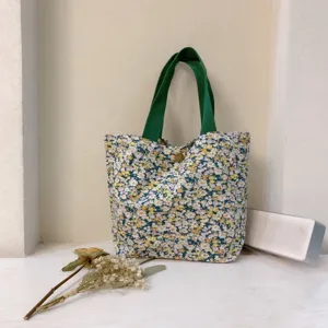 Detailaufnahme der geblümten Segeltuchtasche mit grünen Griffen und floralem Design.