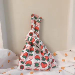 Japanese style knot wrist bag detail, cute strawberry print fabric handbag close up.