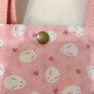 Detailansicht der rosafarbenen japanischen Leinentasche mit niedlichem Hasenmuster und Druckknopf.