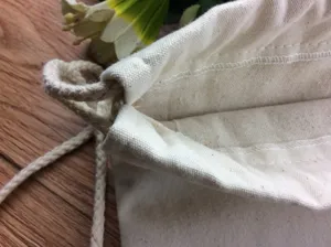 Close-up detail of plain canvas drawstring bag with visible texture and sturdy cotton cord.