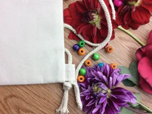 DIY blank canvas drawstring bag detail close-up with floral decor and colorful wooden beads.