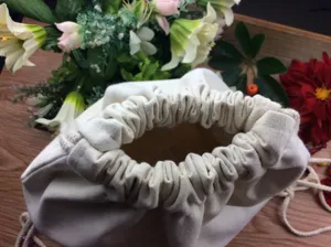 Close-up detail of the cinched opening on a plain white canvas drawstring bag, perfect DIY craft.